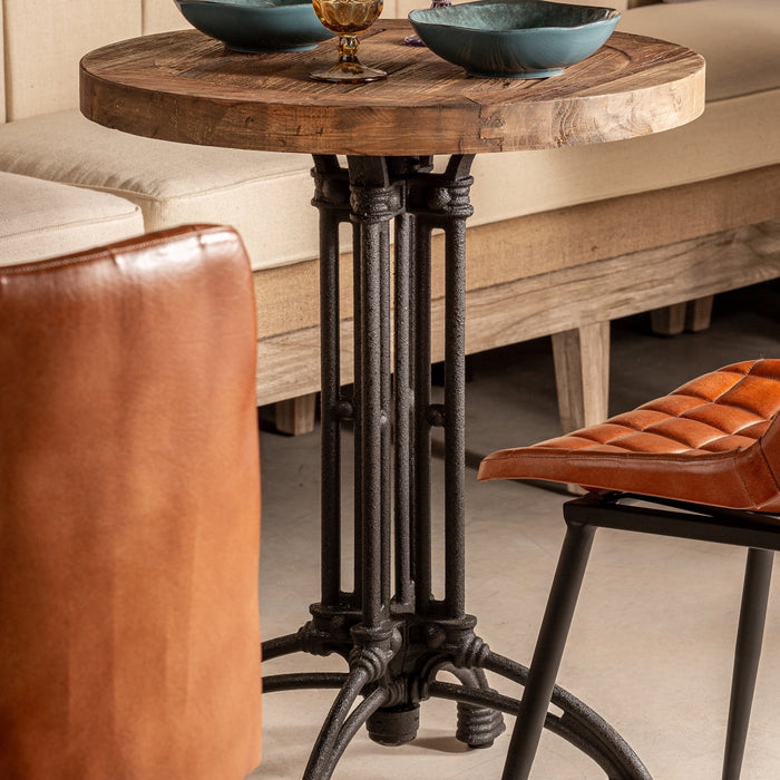 Round Buckie Bar Table, with its striking black and natural tones, captures the raw essence of industrial design. Its robust iron framework harmoniously complements the reclaimed beauty of elm tree wood, showcasing a sustainable touch