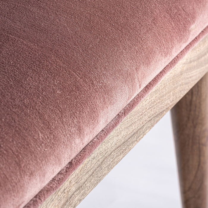 Tardiano bed foot stool, in a charming pink shade, perfectly captures the romantic essence of the shabby chic aesthetic. Carved from mango wood and adorned with plush pink velvet cushioned by foam, it exudes a sense of soft, vintage elegance